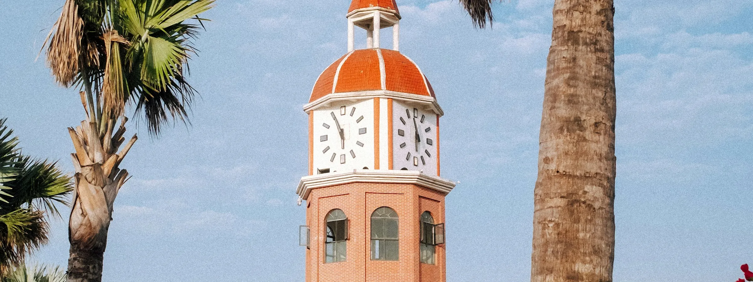 The old customs clock tower among palm trees in Haikou
